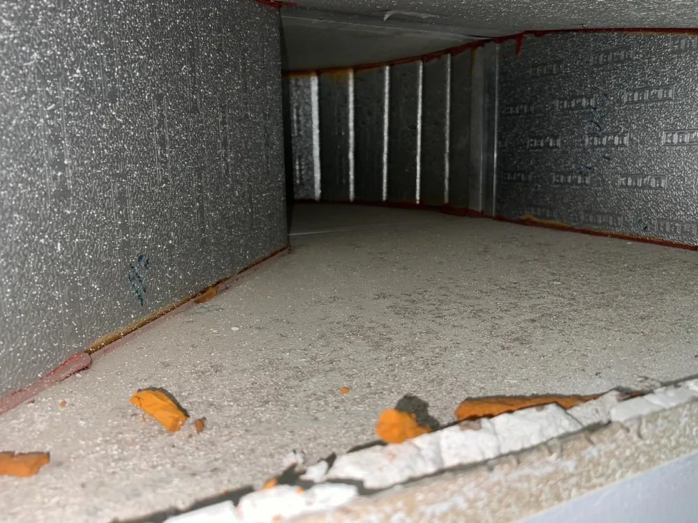 Inside an air duct before deep cleaning, coated in dust and grime