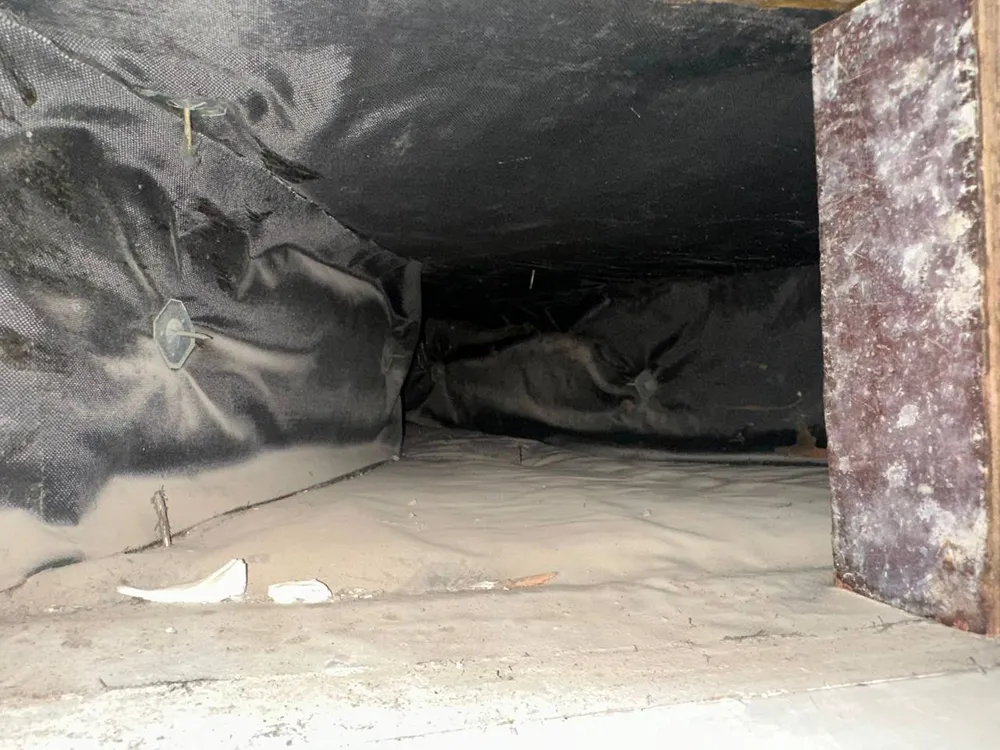 Duct plenum before cleaning, covered in dust and sand